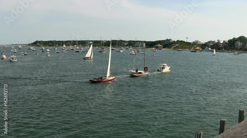 Sailboats passing by the ferry dock between Edgartown and Chappaquiddick Island on Martha's Vineyard during busy summer season.