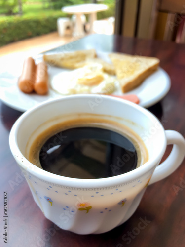 Breakfast concept - cup of black coffee with toasts at the background