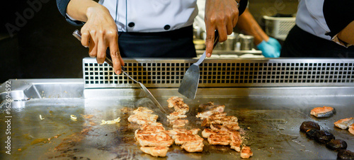 Hand of Chef cooking chicken steak