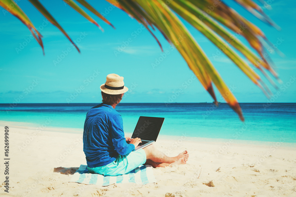 man with laptop on tropical sand beach