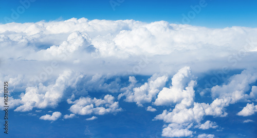 Panoramic view of the massif of the cumulus clouds like a mountains, at the height of 10000 meters (about 6 miles) symbolizing purity and a heavenly dwelling place.
