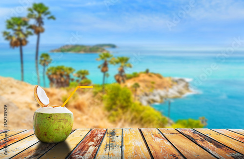 Coconut juice on wood table with Phromthep cape in Phuket island in summer, Summer holiday concept.