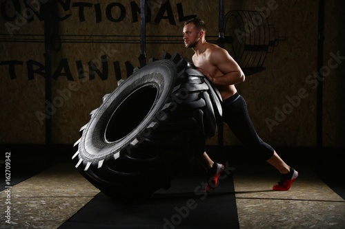 Man pulling tire with knee