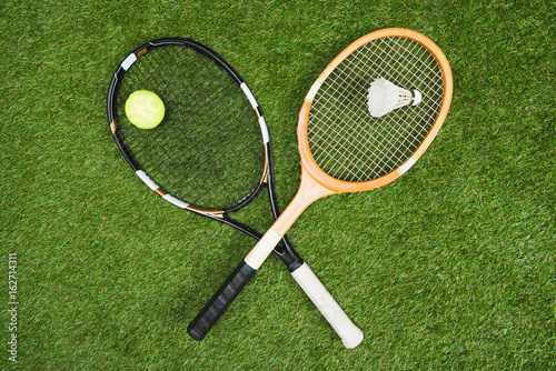 top view of tennis and badminton equipment lying on grassland