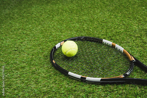 close up view of tennis racket and ball on green lawn