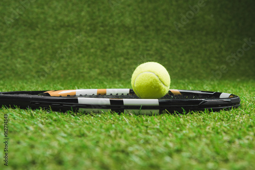 side view of tennis racket and ball on green grassland