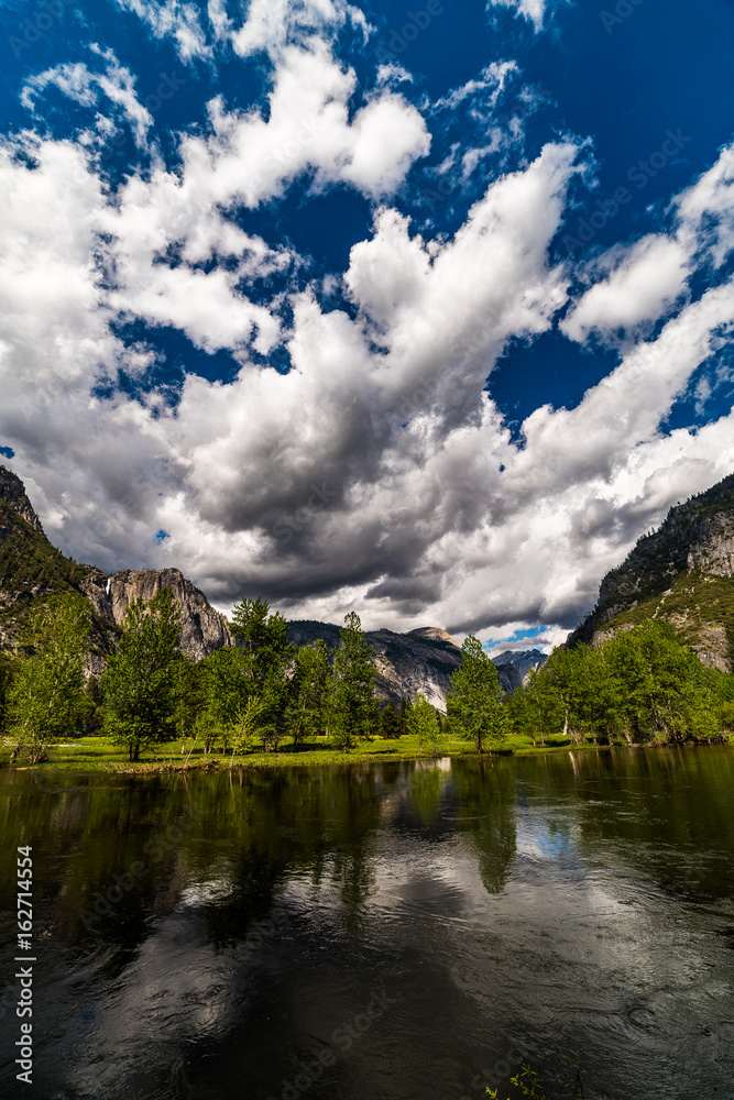 Yosemite with incredible clouds and deep blue skies overhead the river