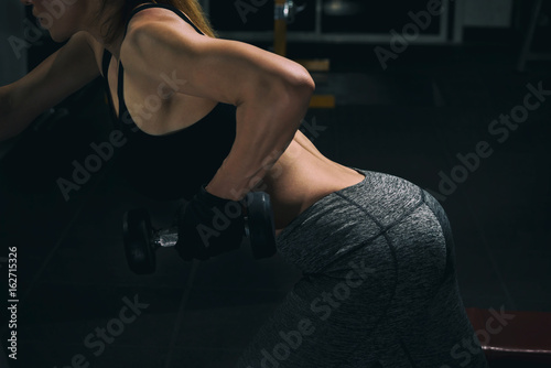 Fitness woman doing dumbbell row for back workout.