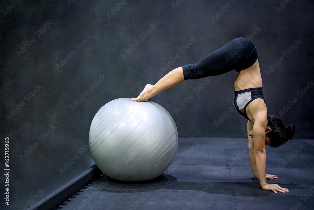Naklejka premium Young Asian athlete woman doing pilates exercises with exercise ball in fitness gym, healthy lifestyle concepts