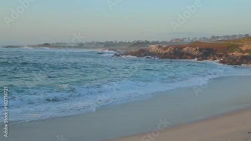 Coastal California ocean beach, cliff and beautiful scenery along coast. Blue water and waves crashing along beach and rocks. Spanish Bay Beach in Pacific Grove. California. Monterey 17 Mile Drive.