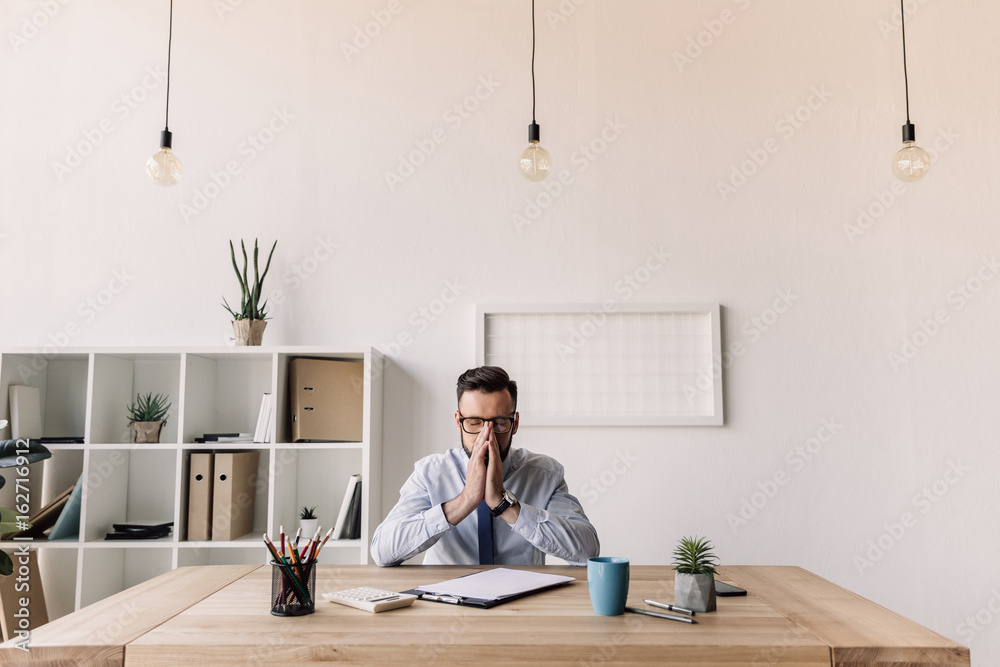 thoughtful bearded businessman sitting at table in modern office thoughtful bearded businessman sitting at table in modern office