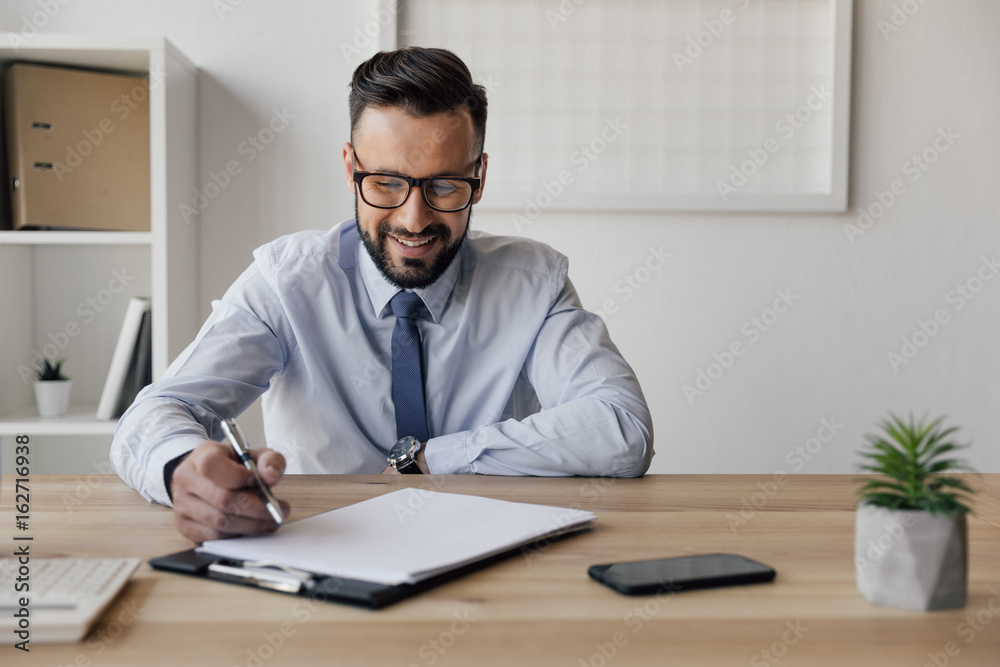 portrait of cheerful businessman with pen in hand looking at blank paper portrait of cheerful businessman with pen in hand looking at blank paper