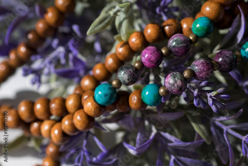 Beautiful wooden beads with gemstones chrysocolla, tourmaline and turquoise on flowers background. Mala beads. rosary for meditation photo