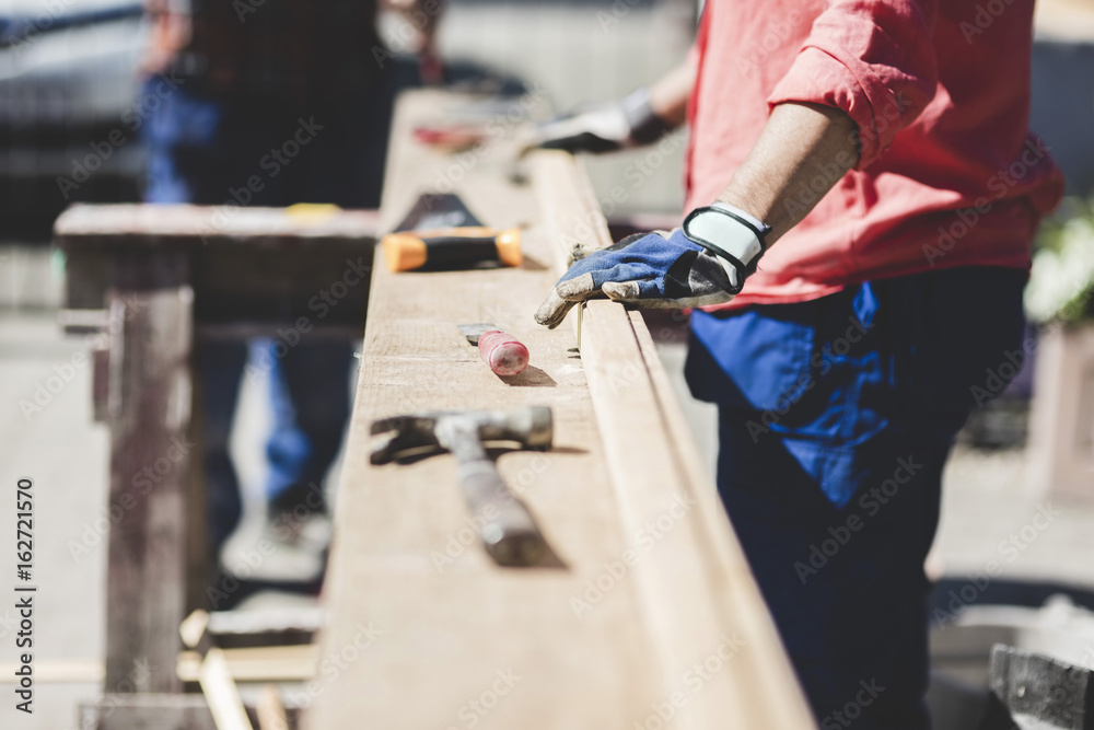 Midsection of senior woman standing by wooden plank in yard during sunny day Midsection of senior woman standing by wooden plank in yard during sunny day