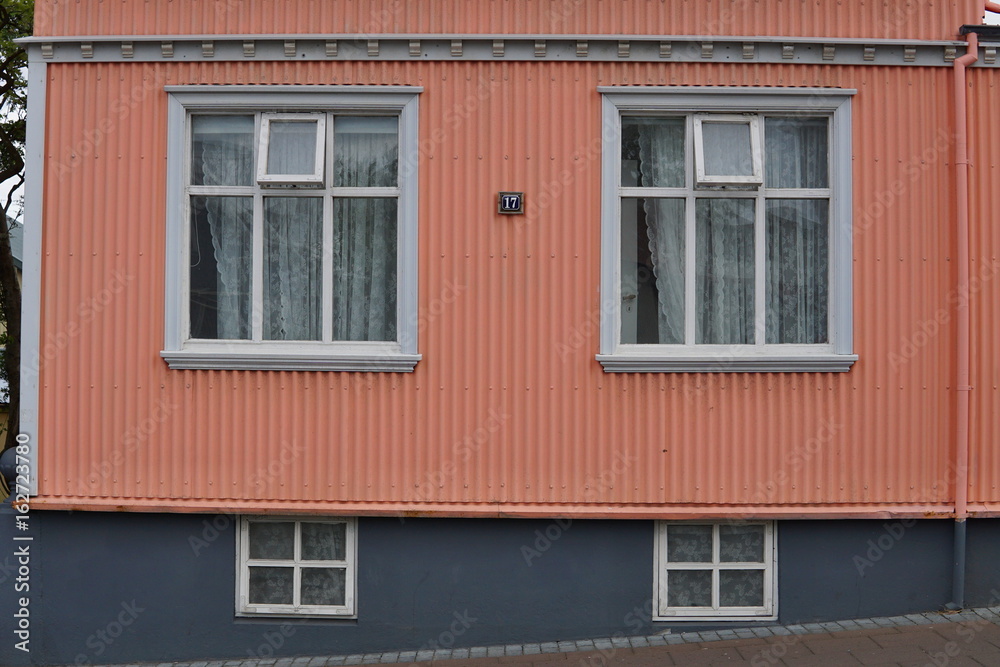 Typical Icelandic house facade in salmon pink color made of corrugated iron and with white wooden windows in Reykjavik (the capital city of Iceland) 