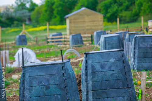 Black plastic compost bin and small wooden cabin in town garden photo