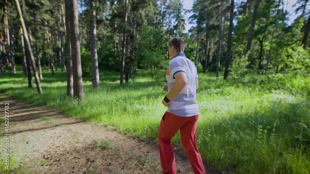 Unrecognizable man in sportswear running in sunlight of summer forest Unrecognizable man in sportswear running in sunlight of summer forest