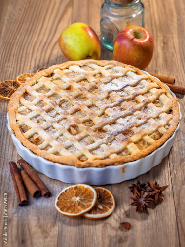 Homemade apple pie and ingredients on a rustic table