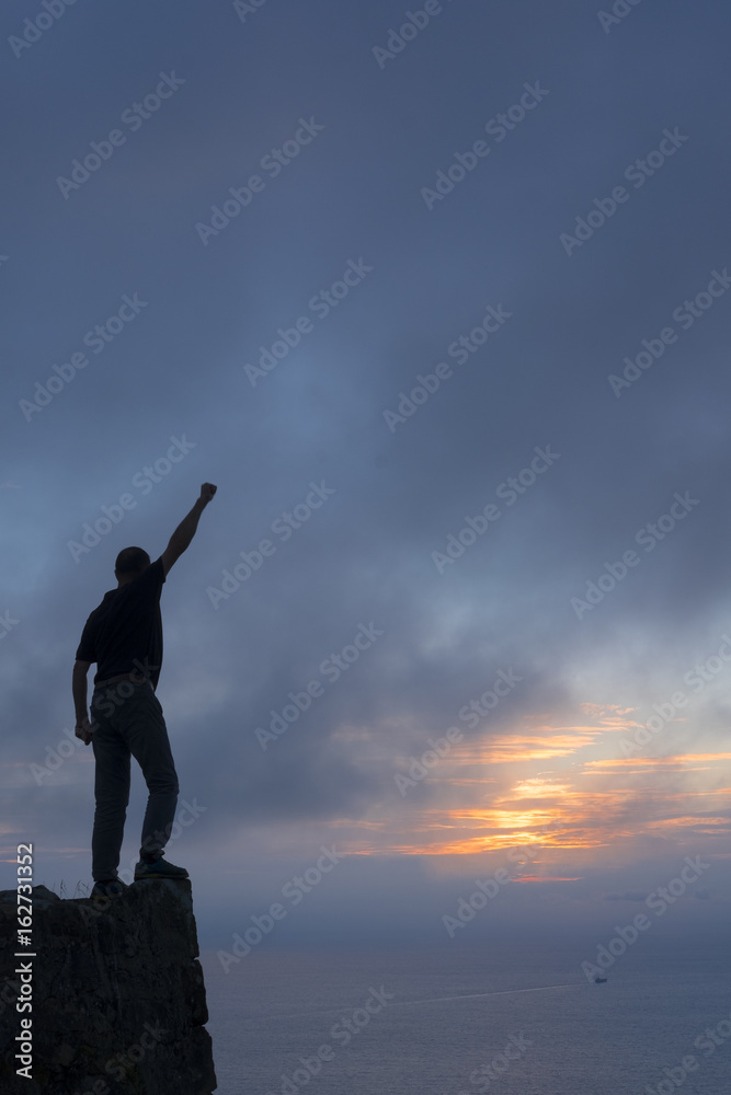 Climber on top of mountain at sunset