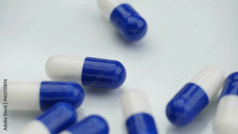Blue pills falling on reflective surface, slow motion
Blue pills falling on reflective surface, slow motion