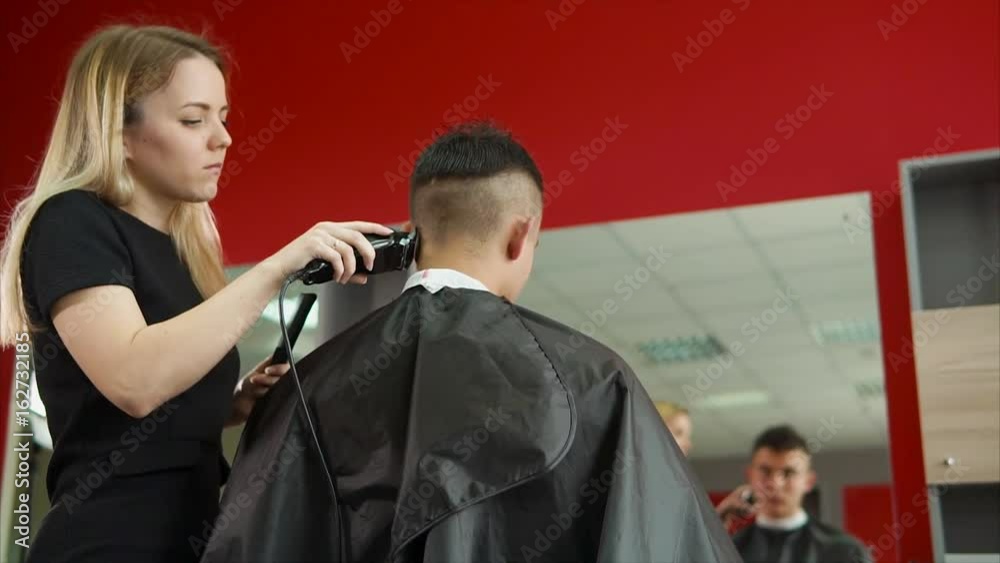 A young and professional hair stylist who works in a hair salon shaves