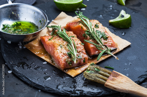 Fotografia Slices of raw salmon smeared with spices and olive oil shale on a plate close-up