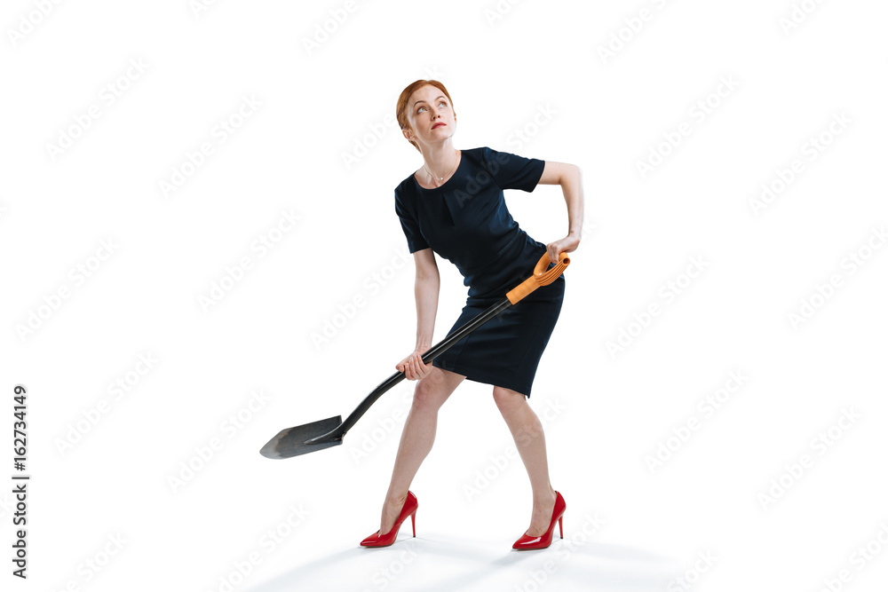 young red haired businesswoman digging with shovel and looking up isolated on white