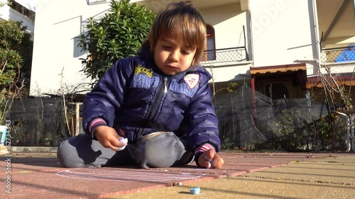 4K Kid enrapt painting on the cement tiles photo