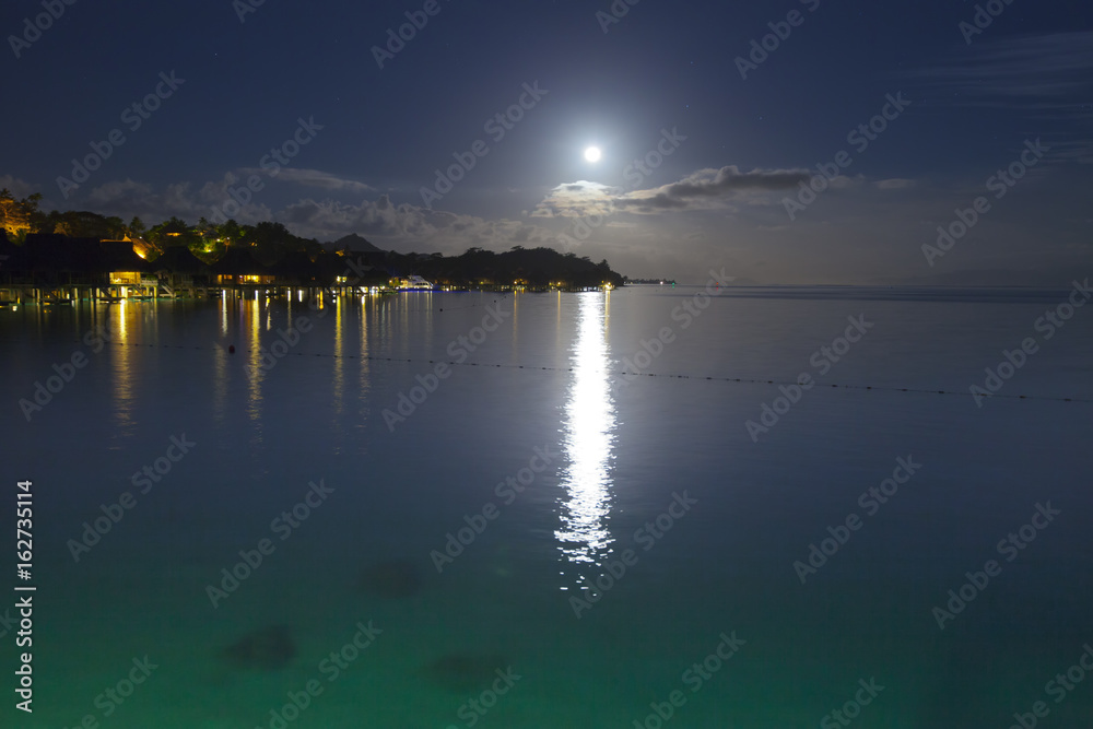 Night. The moon over the sea and reflection in water.