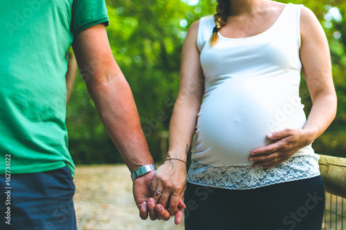 Dettagli Premaman, uomo e donna si tengono per mano e accarezzano la pancia della donna incinta photo