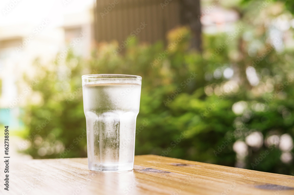 a glass of water on a wooden table. a glass of water on a wooden table.
