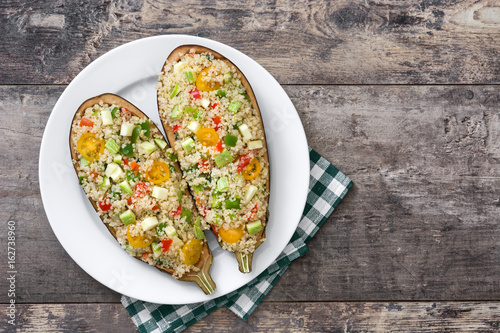 stuffed eggplant with quinoa and vegetables on wooden table photo