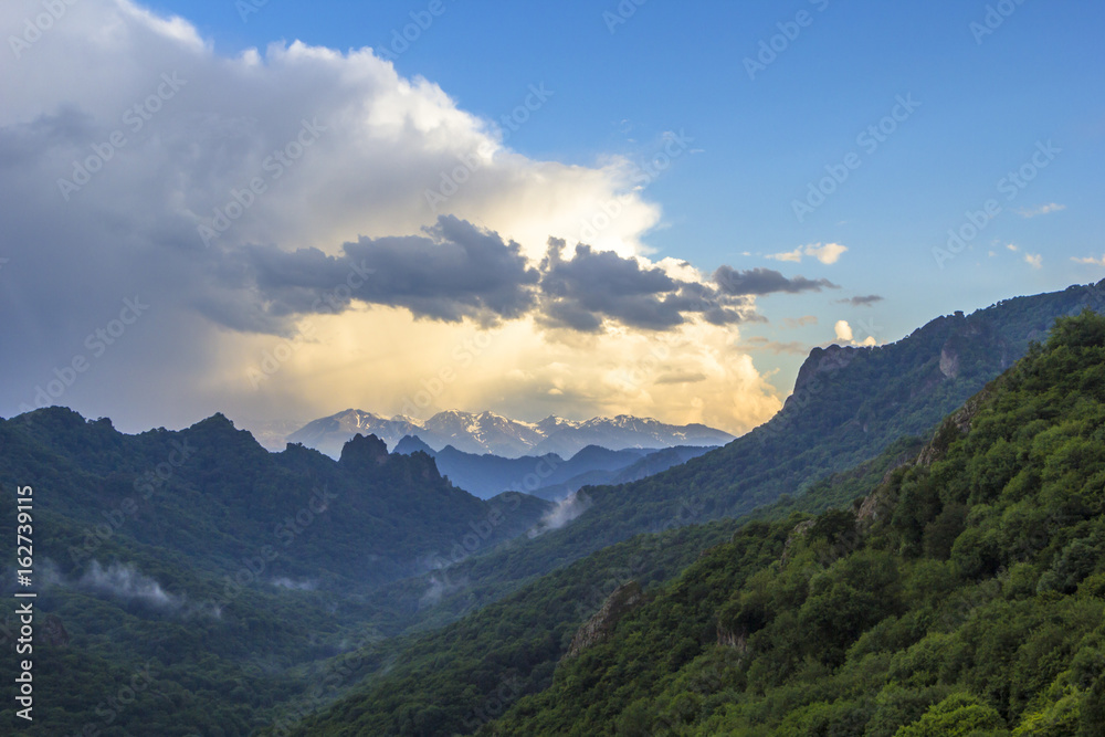 Горный пейзаж, красивый вид на живописное ущелье, облака в синем небе над горами, вечер, дикая природа и горы Северного Кавказа
