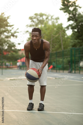 African american man on basketball court dribbling with ball. Real and authentic activity. © antgor