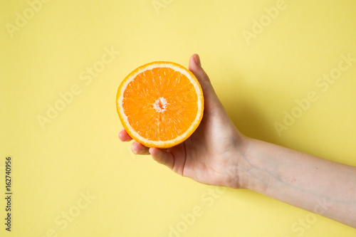 Wallpaper Mural Hand holding orange on yellow background food concept Torontodigital.ca