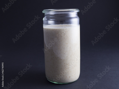 Fresh made sourdough starter in tall glass isolated on black background