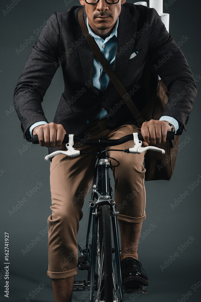Fototapeta premium cropped shot of young businessman with bag riding on bicycle