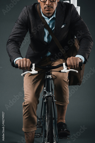 cropped shot of young businessman with bag riding on bicycle © LIGHTFIELD STUDIOS