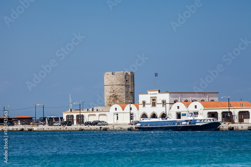 Harbor and monuments in Rhodes. Old defensive stands and windmills. Wharf harbors, boats and sailing ships. Historic harbor, pier and beach.