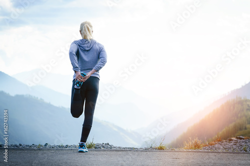 Running stretching. Athlete at the top of the mountain.