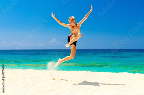 Happy teen boy having fun on the tropical beach. Summer vacation concept