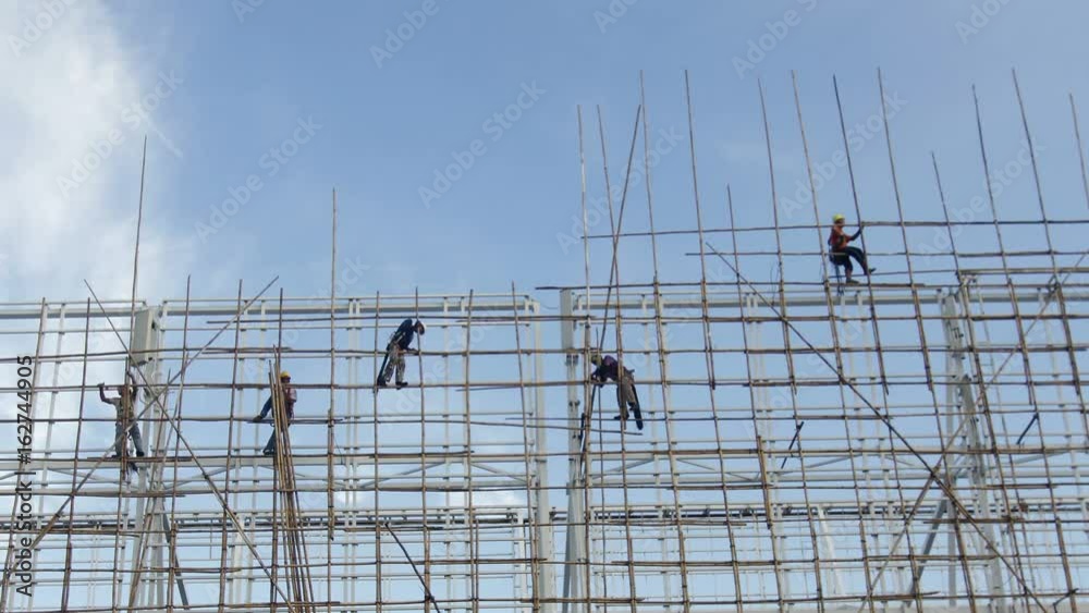 Bamboo scaffolding - Hong Kong construction worker erecting bamboo scaffolding on top of a tall building in Hong Kong.