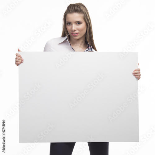 Young happy woman portrait of a confident businesswoman showing presentation, pointing placard gray background. Ideal for banners, registration forms, presentation, landings, presenting concept.. © olharozova