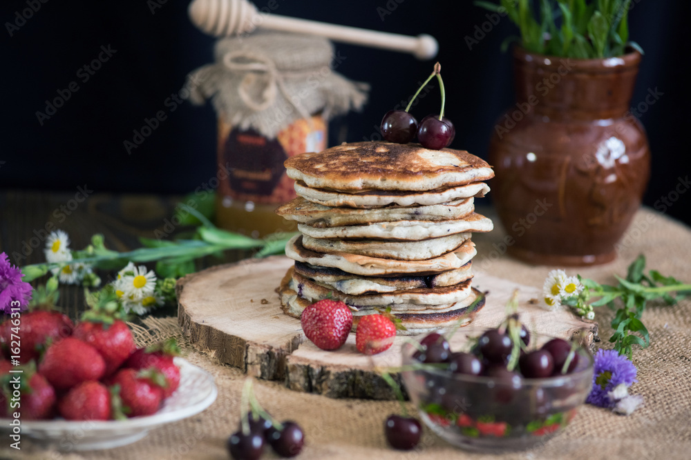 Delicious pancakes with berries on the authentic wooden stand. Summer food still life concept. Delicious pancakes with berries on the authentic wooden stand. Summer food still life concept.