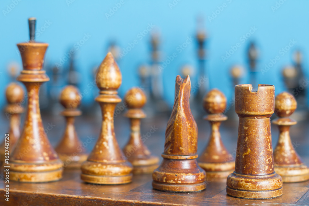 Fototapeta premium Vintage wooden chess pieces on an old chessboard.