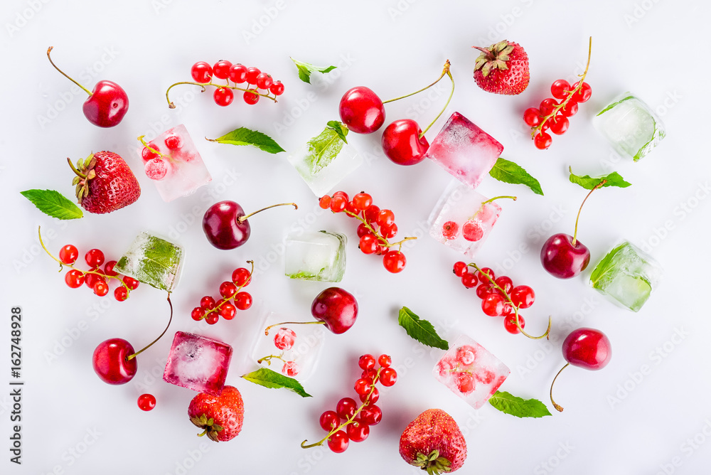 Top view ice cubes with fresh berries among not frozen cherry, strawberry and mint leafs on the white background. Selective focus Top view ice cubes with fresh berries among not frozen cherry, strawberry and mint leafs on the white background. Selective focus