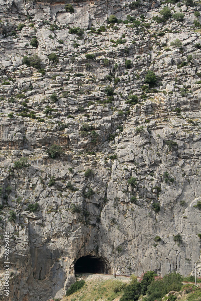 The train tracks crossing the rock through a tunnel, in Caminito del Rey, Malaga, Spain