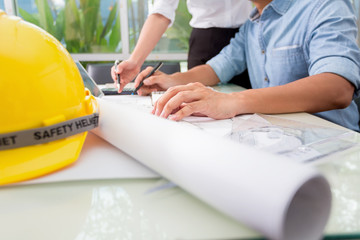 Hands of engineer working with the tool on project drawings background at construction site