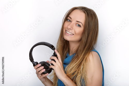 Headshot of young adorable blonde woman with cute smile wearing big black professional monitoring headphones against white studio background