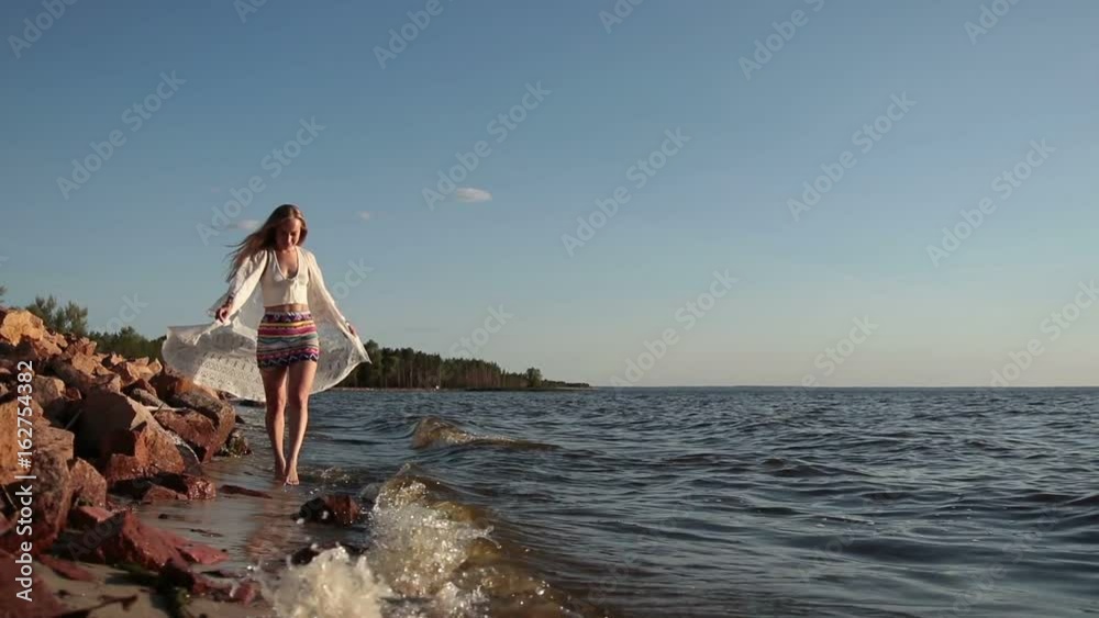 Barefoot woman walking on seaside at golden sunset Barefoot woman walking on seaside at golden sunset